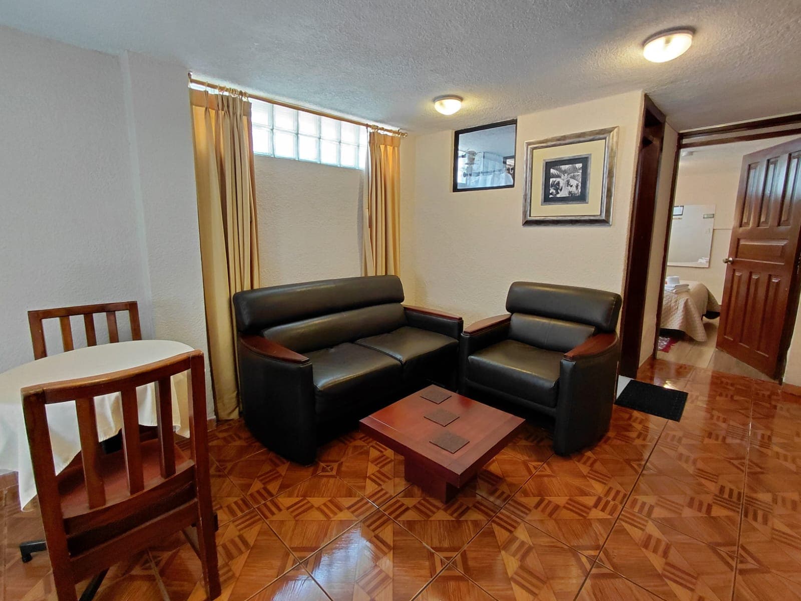 Sala común con sofás de cuero y mesa de centro en hostal de Quito