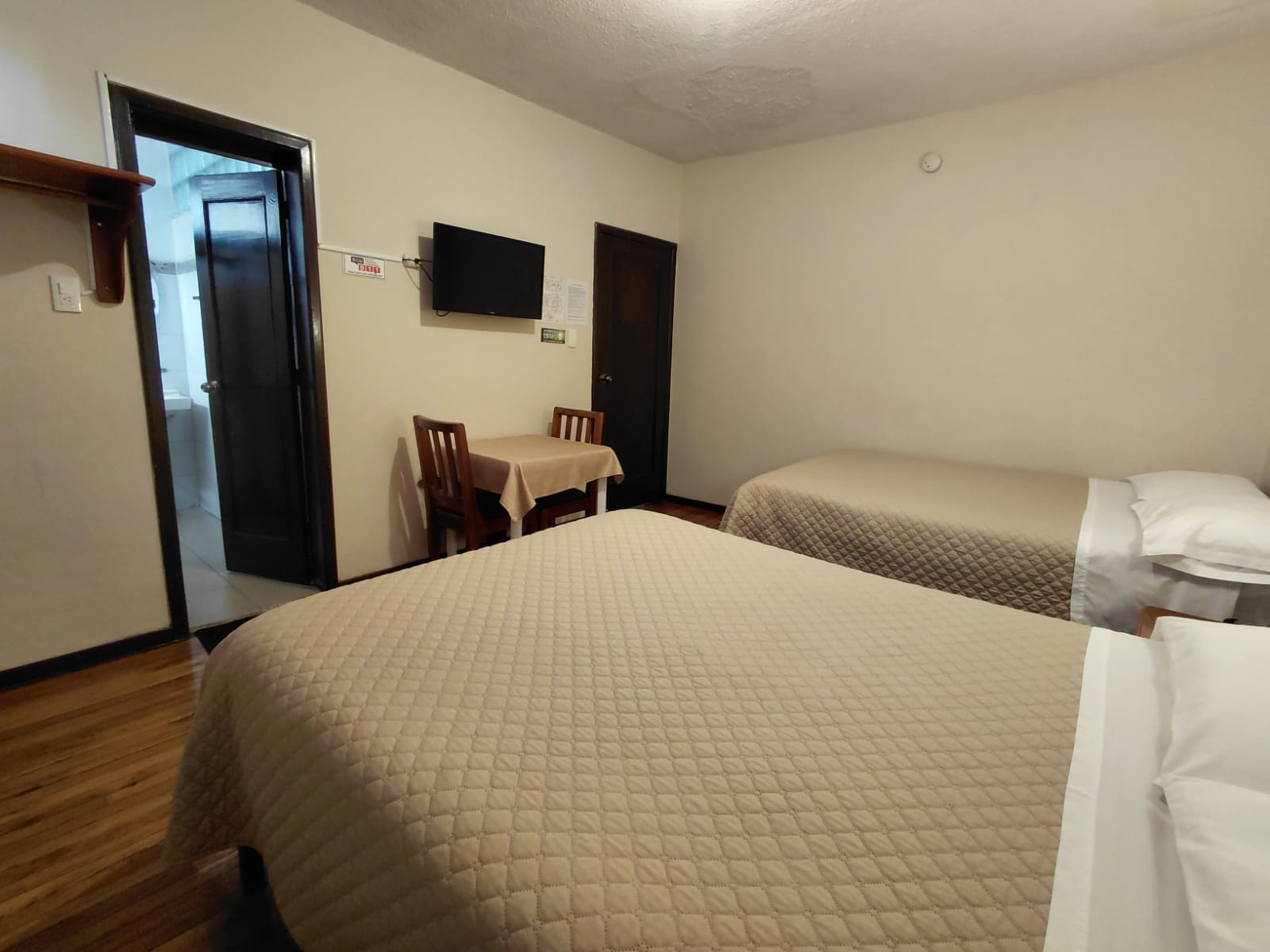 Habitación doble con baño privado, TV pantalla plana y mesa en hostal Quito