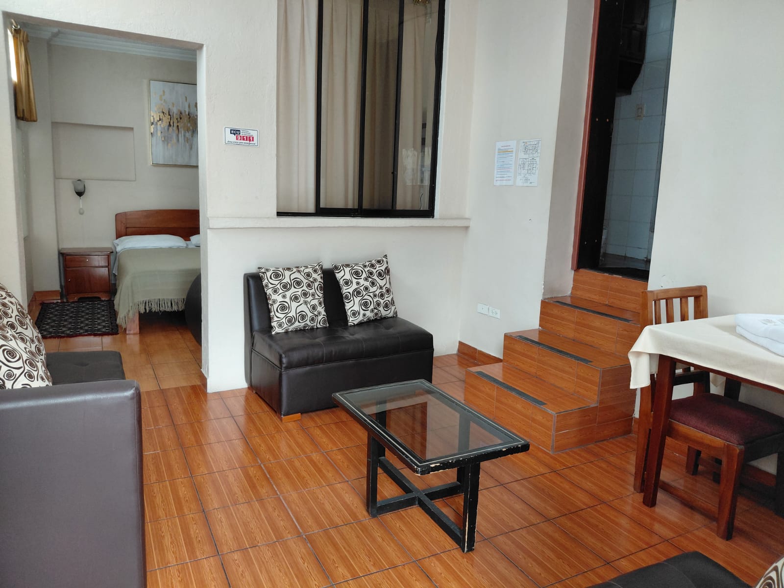 Suite privada con sala de estar, sofá de cuero y escalones de madera en hostal Quito