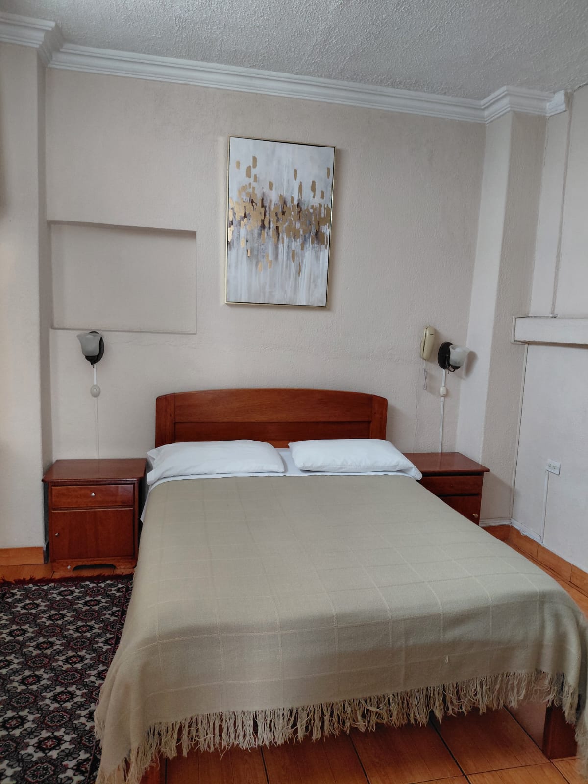 Suite privada con cama queen, mesitas de noche y alfombra elegante en hostal Quito
