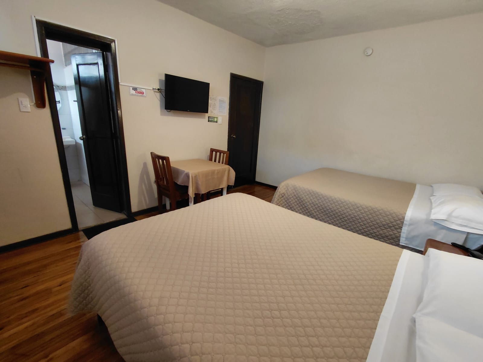 Habitación doble con baño privado, mesa de trabajo y TV en hostal de Quito
