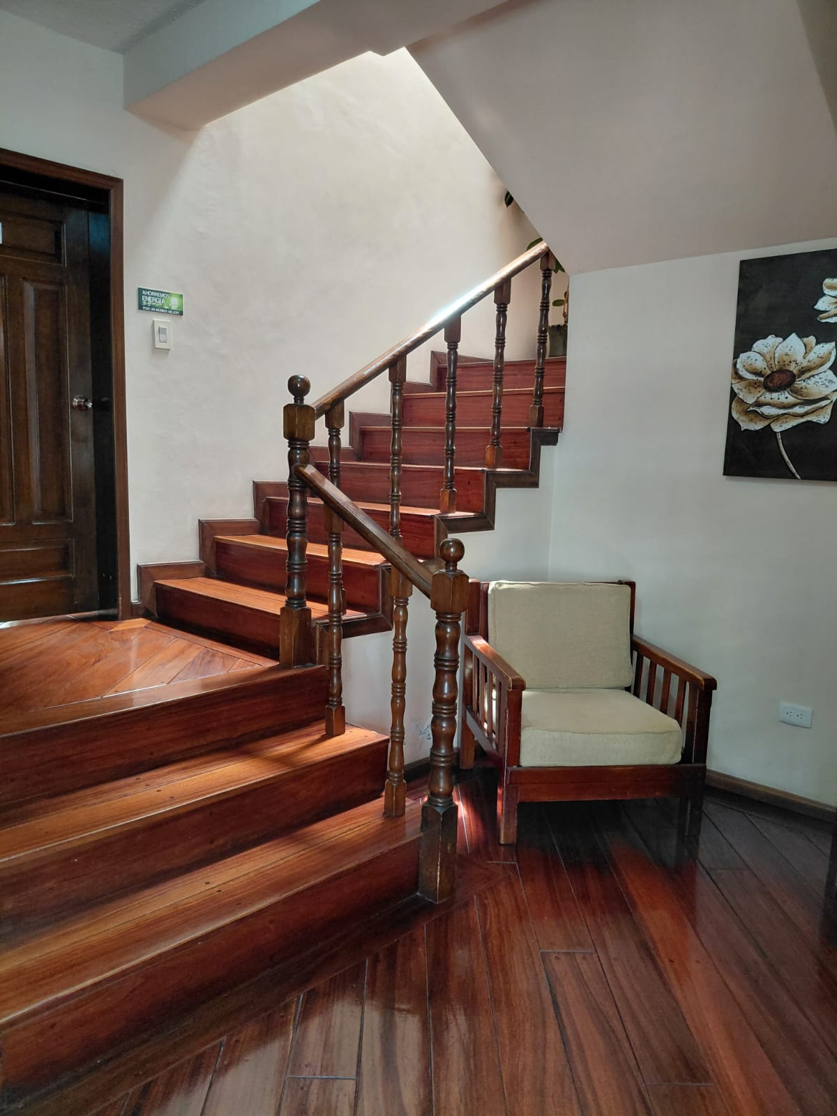Escalera de madera clásica con sillón en hostal tradicional de Quito