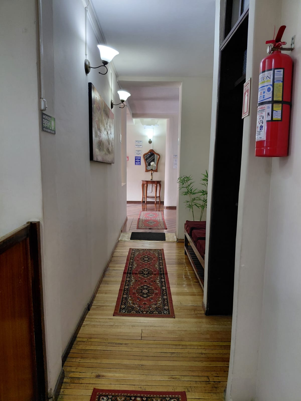 Pasillo con alfombras persas y decoración clásica en hostal de Quito