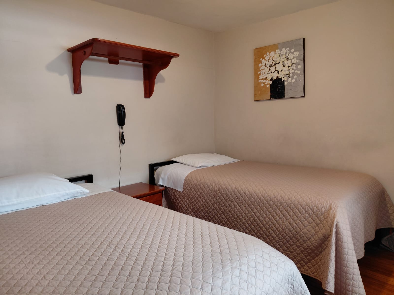 Habitación económica con dos camas individuales y decoración sencilla en hostal Quito