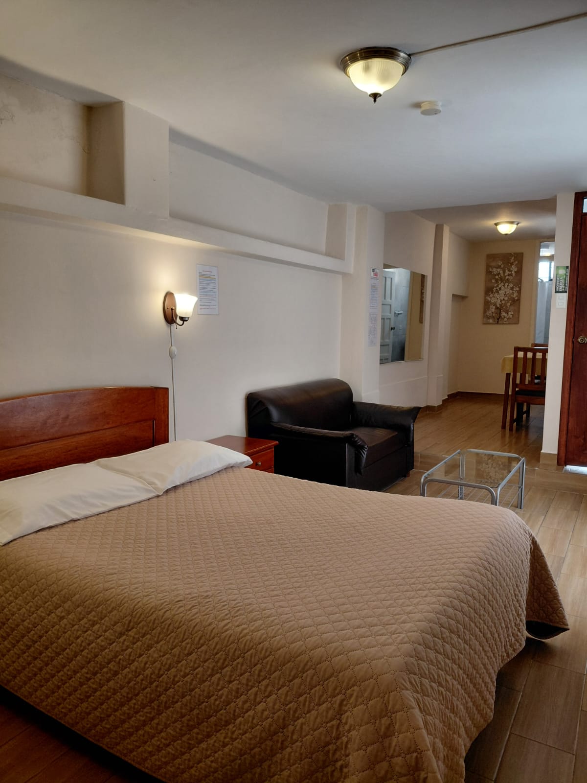 Suite amplia con cama queen, sofá y zona de estar en hostal de Quito