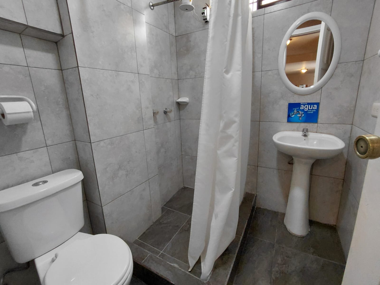 Baño privado moderno con ducha, lavamanos y espejo en hostal de Quito