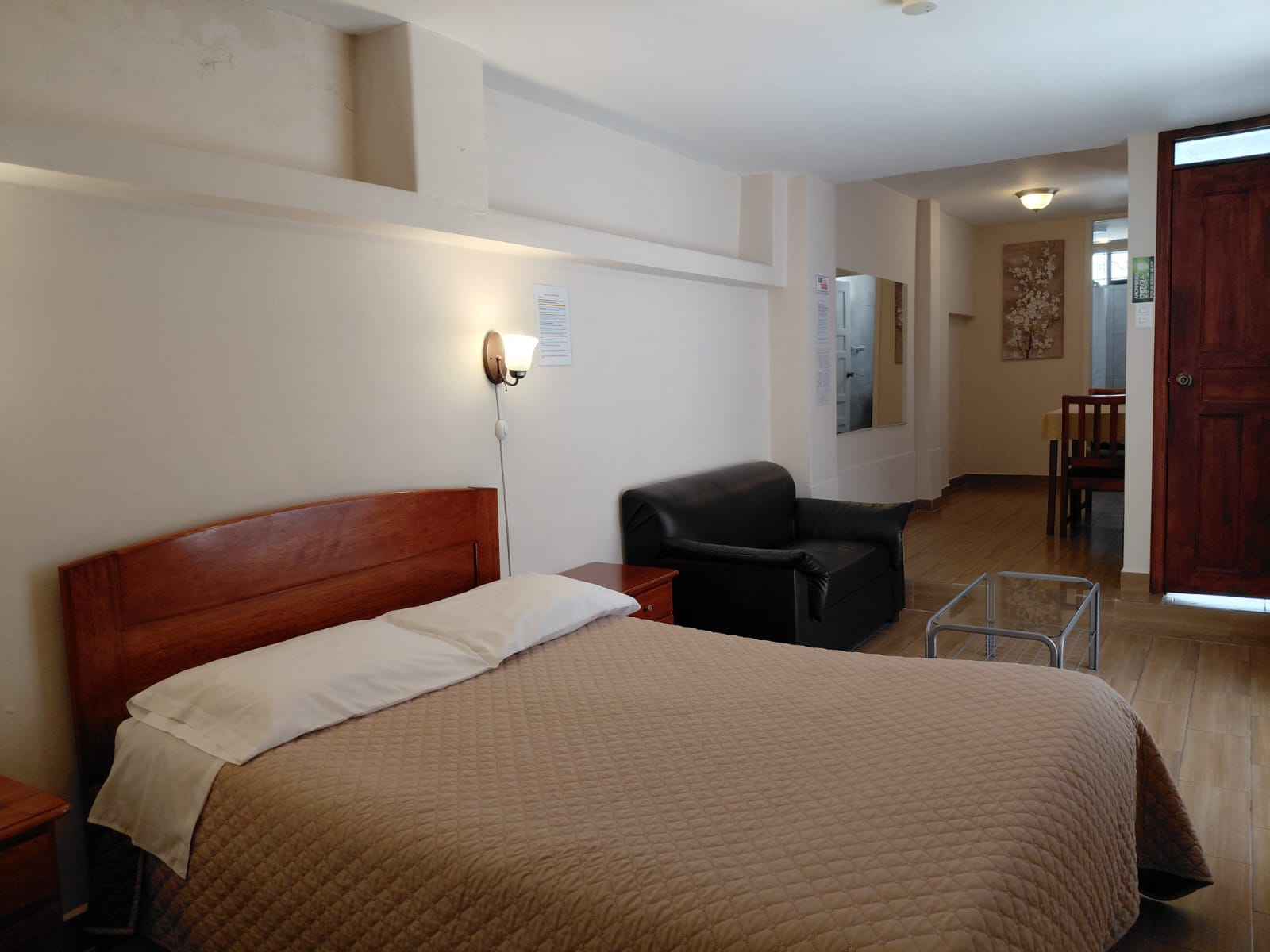 Suite con cama queen, sala de estar y escritorio en hostal céntrico de Quito